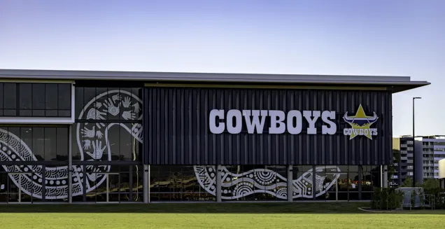 HERO NQ Cowboys Community, Training and High-Performance Centre front view of exterior with indigenous snake artwork on glass and cowboys logo with grass in the foreground
