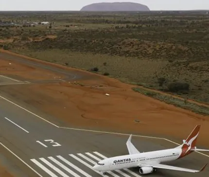 aerial view of Connelan Airport runway overlooking Uluru and a QANTAS plane in Yulara